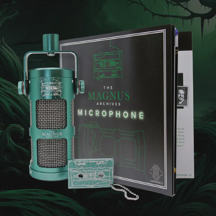 A photograph of a green microphone engraved with The Magnus Archives logo. Next to the mic is a large booklet and a cassette tape keychain.